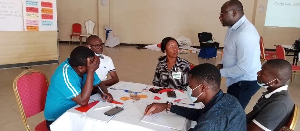 Participants en travail de groupe autour d'une table avec un facilitateur